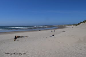 South Beach State Park, Newport, Oregon: A wide, sandy beach with a few people walking and relaxing, clear blue sky, and gentle ocean waves in the background.