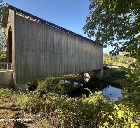 Chambers Covered Railroad Bridge in Oregon: The picture "Chambers Covered Railroad Bridge in Oregon bridge over river reflection" features the exterior of the covered bridge crossing a calm river, with the structure and surrounding trees reflected in the water below.