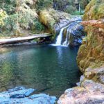 Blue Hole Falls on Brice Creek in Oregon: The picture "Blue Hole Falls waterfall and pool closeup" displays a close view of the waterfall cascading into the iconic deep blue-green pool, with mossy cliffs and fallen logs framing the clear, tranquil water.