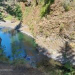 Molalla Eye, Oregon: Scenic Swimming & Fishing Spot on the Molalla River – Molalla Eye Aerial Rim Molalla Eye, Oregon: Scenic Swimming & Fishing Spot on the Molalla River – The picture "Molalla Eye Aerial Rim" is a high perspective shot looking down into the river’s vivid blue-green waters as swimmers relax along the semi-circular stone bank of a narrow, winding canyon.